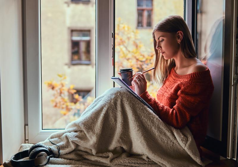 A person reading in an armchair by a window on a quiet afternoon with a cup of tea