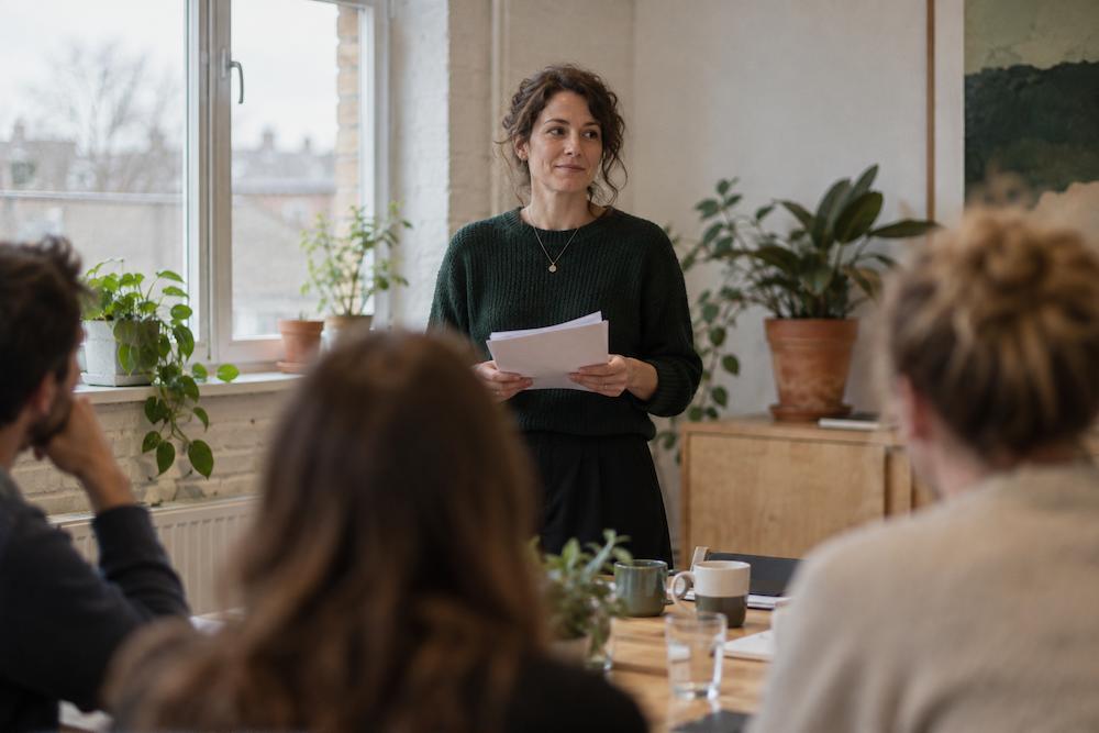 Someone standing at the front of a small meeting room about to speak